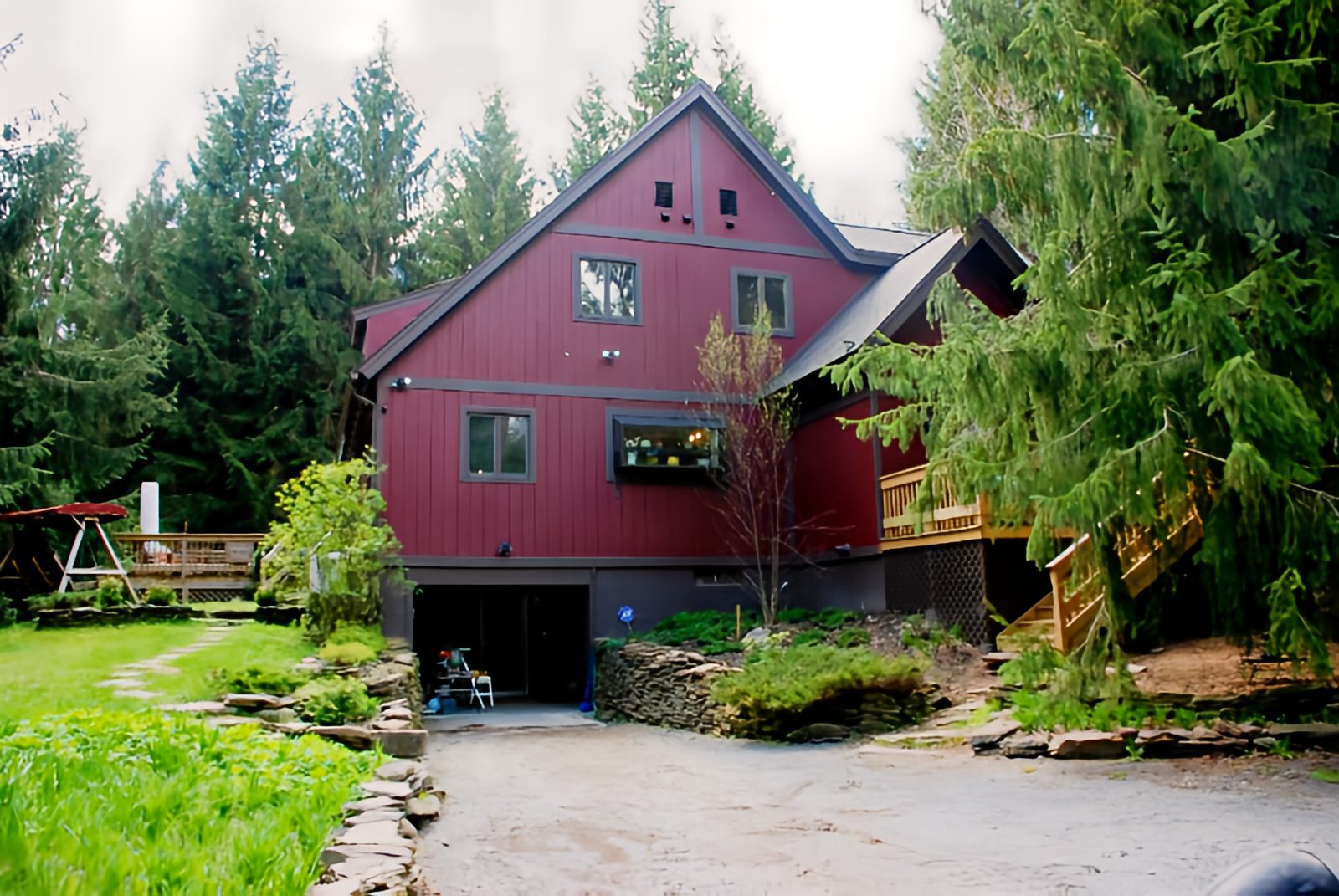 Red house surrounded by trees and garden.