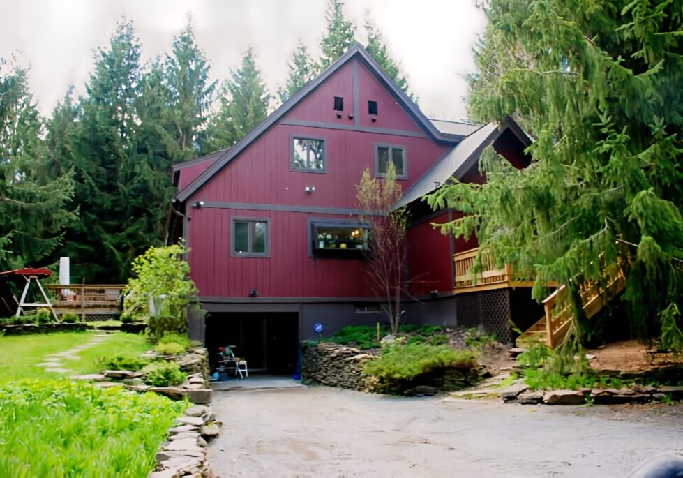 Red house surrounded by trees and garden.